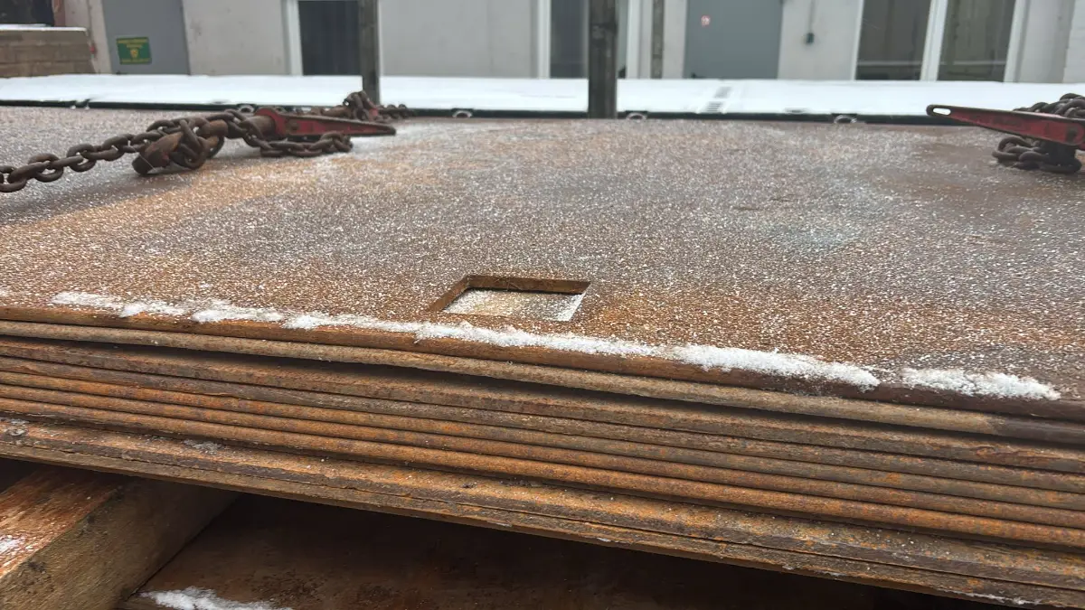 Gestapelte Stahlplatten mit Ankerpunkten auf Lagerplatz im Winter
